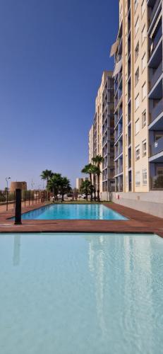 une grande piscine en face de certains bâtiments dans l'établissement Apartamento Rokita Blanca, à La Manga del Mar Meno