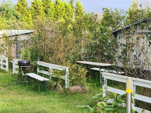 a garden with white benches and a fence at Camping - Park Władysławowo in Władysławowo