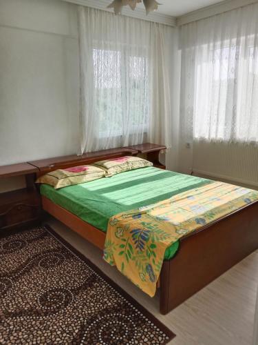 a bedroom with a bed with a green comforter at Çetin apart in Ezine
