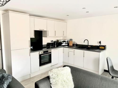 a kitchen with white cabinets and a couch at Mill Bank Apartment in Todmorden
