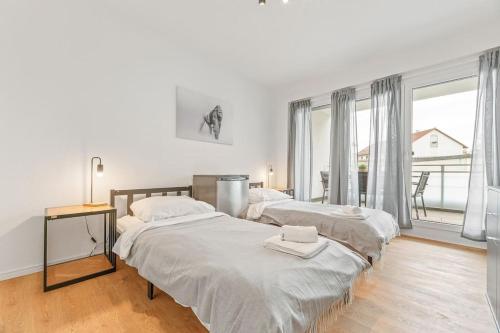 een slaapkamer met 2 bedden en een groot raam bij Großzügiges Business Apartment Herrenberg - Self Check-In in Herrenberg
