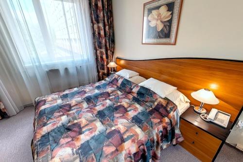 ドゥナウーイヴァーロシュにあるクラブ ホテルのベッドと電話が備わるホテルルームです。