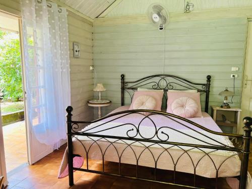 a bedroom with a bed with pink pillows at La Kaz LANGEVIN in Saint-Joseph