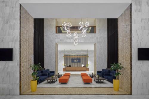 a lobby with orange chairs and a stage in the background at voco Makkah an IHG Hotel in Makkah