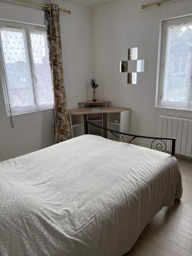 un lit blanc dans une chambre avec deux fenêtres dans l'établissement Chez Laeti appartement type F2, à Fécamp