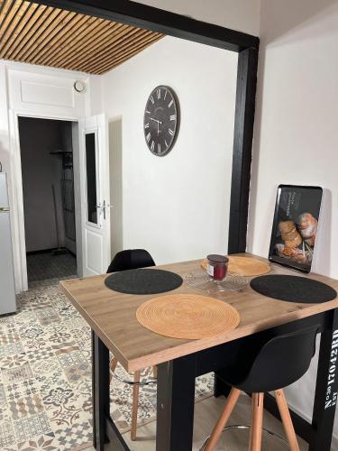 une table à manger avec une horloge sur le mur dans l'établissement Chez Laeti appartement type F2, à Fécamp