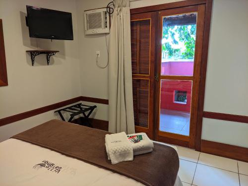 a bedroom with a bed and a window with a television at Pousada Villegaignon in Búzios