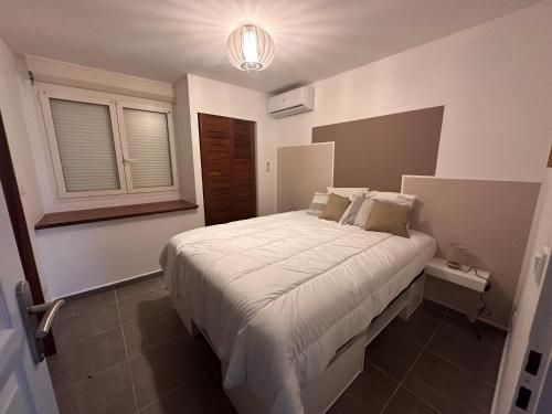 - une chambre avec un grand lit blanc et une fenêtre dans l'établissement T2 Cosy vue mer Petit-Bourg, à Petit-Bourg