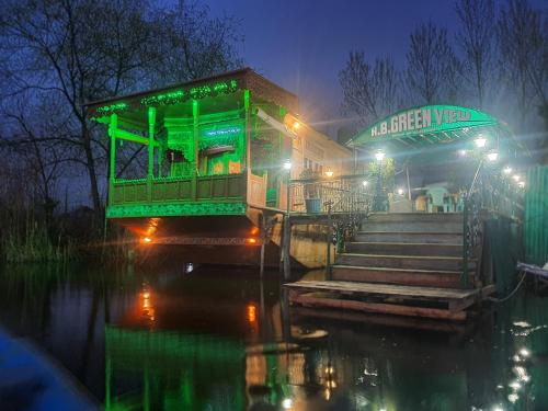 un bâtiment vert sur l'eau la nuit dans l'établissement Green view group of houseboats, à Srinagar