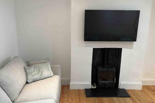 a living room with a couch and a television on a wall at One Bed Flat With Garden in London