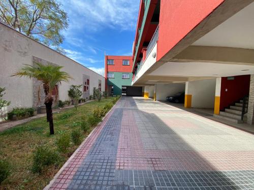an empty walkway next to a building with a palm tree at Elegante departamento en Mendoza in Mendoza