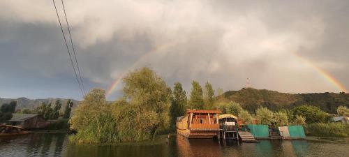 a rainbow over a river with a boat in the water at Green view group of houseboats in Srinagar