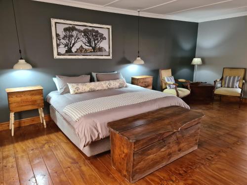 1 dormitorio con 1 cama grande y suelo de madera en Avondrust Guest House, en Klaarstroom