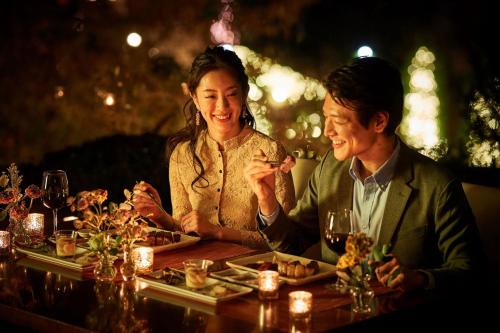 a man and woman sitting at a table with food at Sheraton Grande Tokyo Bay Hotel in Urayasu