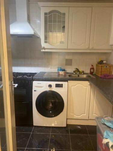 een keuken met een wasmachine en een wastafel bij Quiet flat with a private spacious room in Birmingham