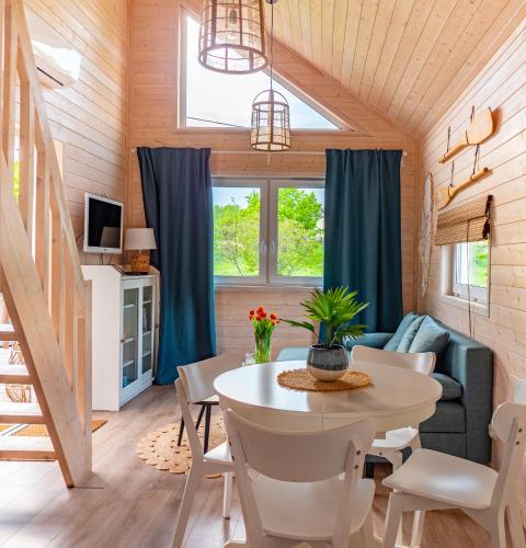 a dining room and living room with a table and chairs at Domek ArkaSasino z jacuzzi in Sasino