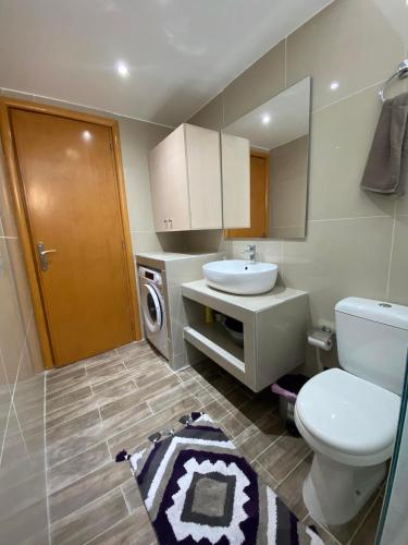 a bathroom with a toilet and a sink and a washing machine at Nesèa Apartment Faliraki in Faliraki