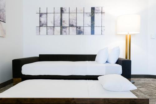 2 Betten in einem Zimmer mit einem Tisch und einer Lampe in der Unterkunft SpringHill Suites by Marriott Dallas Lewisville in Lewisville