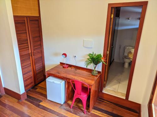a desk with a pink chair in a room with a toilet at Pousada Villegaignon in Búzios