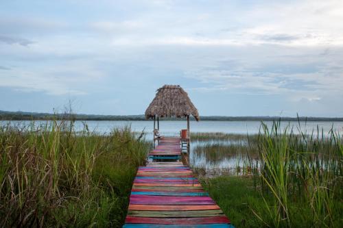 a path leading to a beach with a straw umbrella at Alice Guesthouse in El Remate