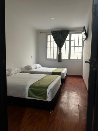 two beds in a bedroom with a window at Hotel Artistico in Bogotá