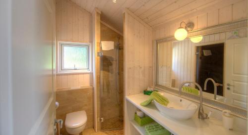 a bathroom with a sink and a toilet and a mirror at Timmenhus - Ferienhäuser am Feldrand in Timmendorfer Strand