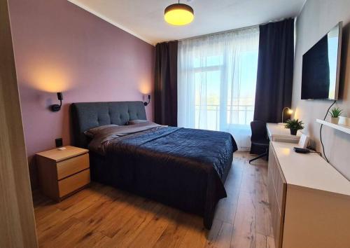 - une chambre avec un lit et une grande fenêtre dans l'établissement Stylish apartment with parking & spacious balcony, à Riga