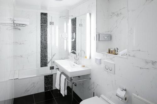 a white bathroom with a sink and a toilet at Grand Hotel Suisse Majestic, Autograph Collection in Montreux