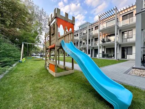 un parque infantil con un tobogán azul frente a un edificio en Zamárdi Margittai Apartmanok en Zamárdi