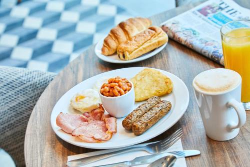 a table with two plates of breakfast food and a cup of coffee at Residence Inn by Marriott London Kensington in London