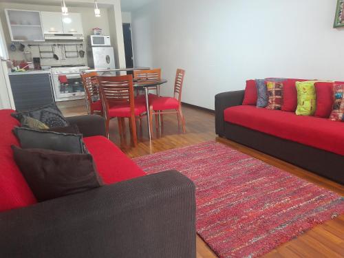 a living room with a red couch and a table with chairs at Departamento acogedor para viajeros y turistas in Mexico City