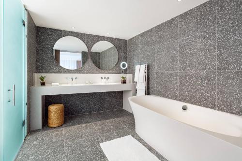 a bathroom with a tub and a sink and a mirror at Malta Marriott Resort & Spa in St Julian's