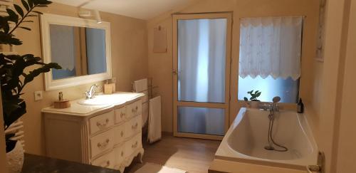 a bathroom with a tub and a sink and a window at La Santon Chambres d'hôtes in Vif
