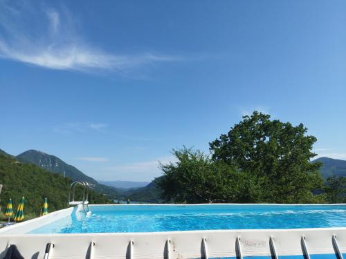 a swimming pool with chairs and mountains in the background at Agriturismo le cascine in Castel di Tora