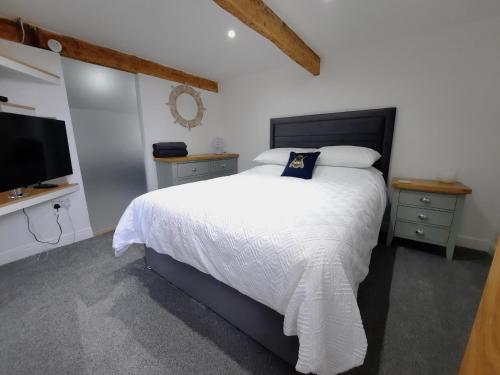 a bedroom with a bed with a white bedspread and a television at The Penthouse, top floor of a Grade II Listed Mill in Praze an Beeble