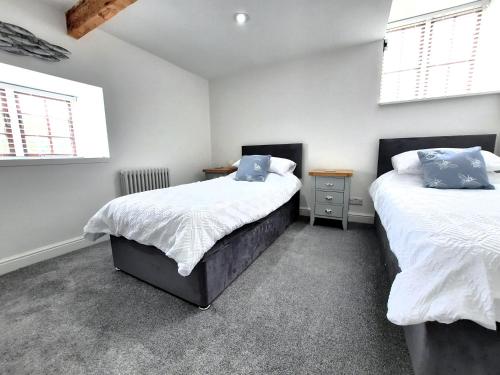 two beds in a room with white walls and windows at The Penthouse, top floor of a Grade II Listed Mill in Praze an Beeble