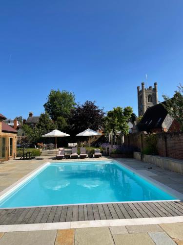 una piscina con sillas y una iglesia de fondo en The Pool House, en Henley on Thames