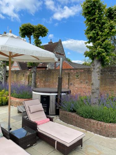 un patio con sombrilla, sillas y parrilla en The Pool House, en Henley on Thames
