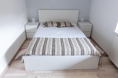 a white bed in a small bedroom with two night stands at Apartament - Bystra in Bystra