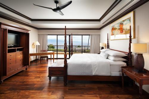 a bedroom with a bed and a television and a balcony at Sheraton Maui Resort & Spa in Lahaina