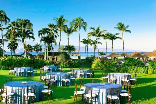 a group of tables and chairs with the ocean in the background at Sheraton Maui Resort & Spa in Lahaina