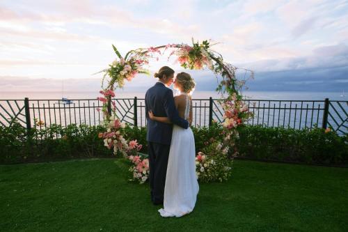 a bride and groom standing under an arch of flowers at Sheraton Maui Resort & Spa in Lahaina