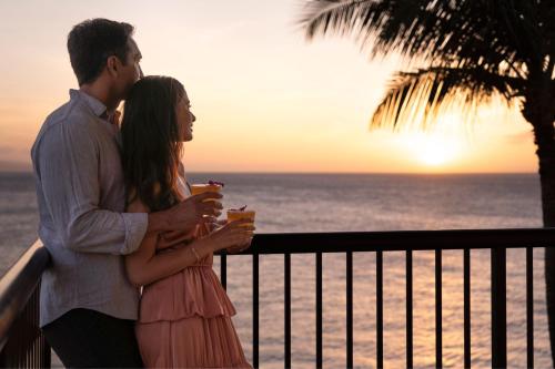 a man and woman standing on a balcony watching the sunset at Sheraton Maui Resort & Spa in Lahaina