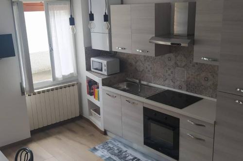 a kitchen with white cabinets and a sink and a microwave at Dream House in Clusone