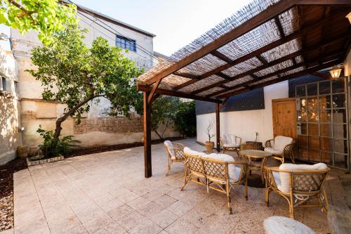 patio z drewnianą pergolą, stołami i krzesłami w obiekcie הסמטה של יפו w Tel Awiwie