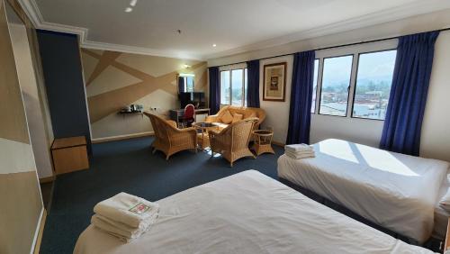 um quarto de hotel com duas camas e uma mesa e cadeiras em Fair Park Hotel em Ipoh