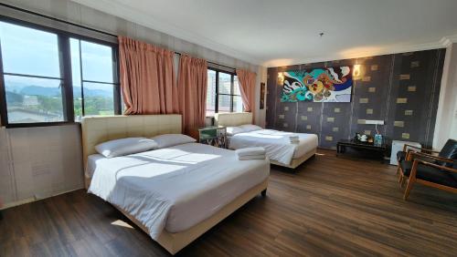 a bedroom with two beds and a painting on the wall at Fair Park Hotel in Ipoh