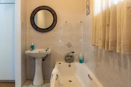 a bathroom with a tub and a sink and a mirror at El Sali Guest House in Hilton