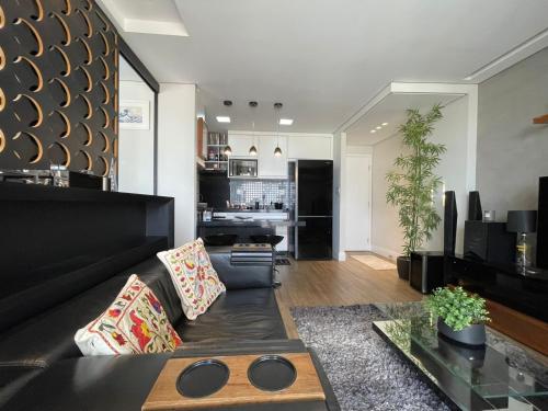 sala de estar con sofá negro y mesa en Studio Deluxe - Dot 173, en Campinas
