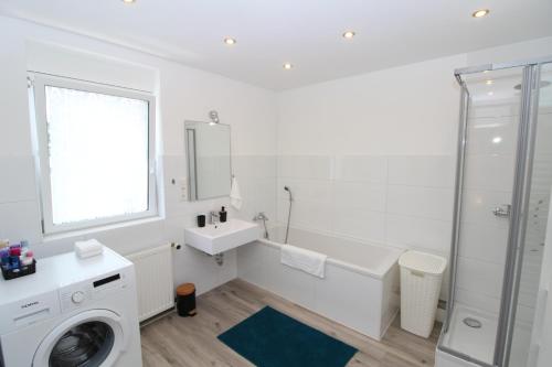 ein weißes Badezimmer mit einem Waschbecken und einer Waschmaschine in der Unterkunft Top ausgestattete Stadtwohnung in Aschaffenburg